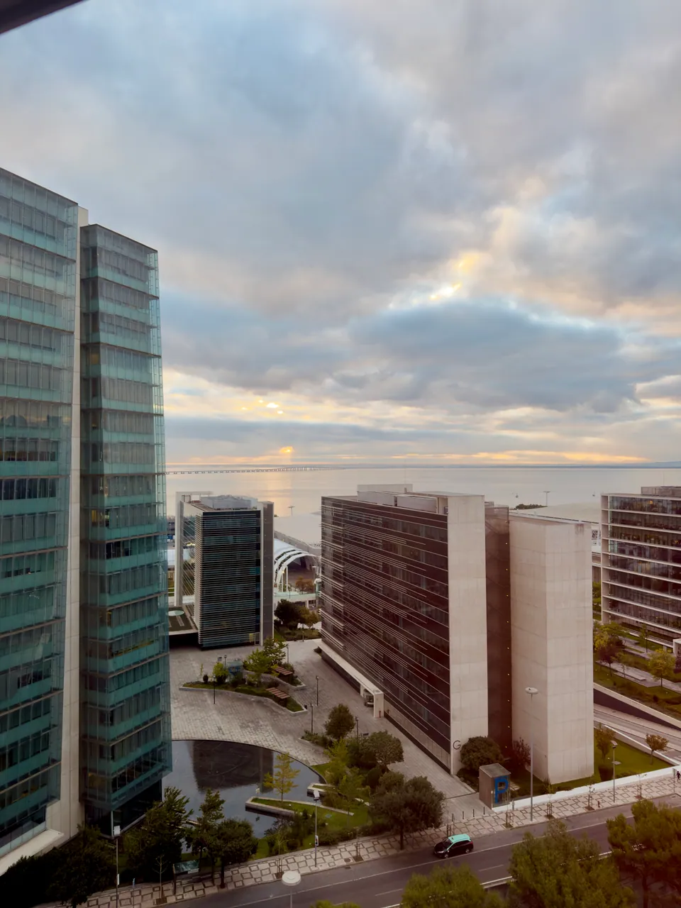 A view between modern buildings towards the waterfront in Lisbon at sunset.