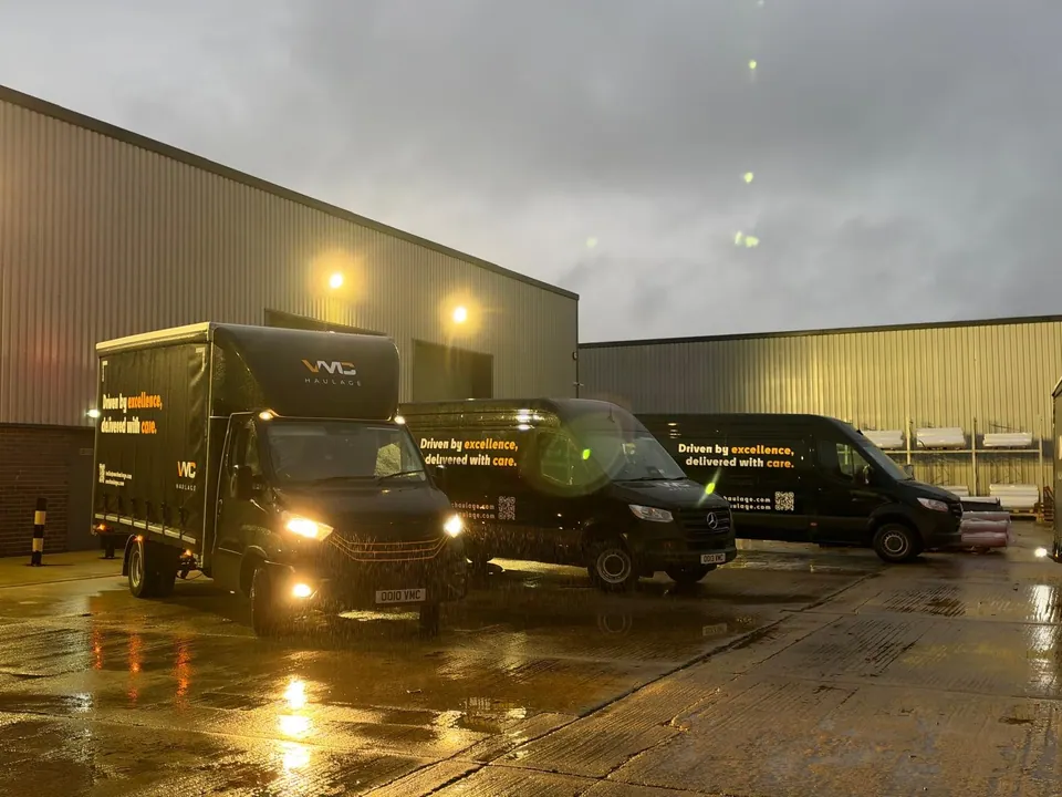 Three black VMC Haulage vehicles outside the warehouse in wet evening conditions.